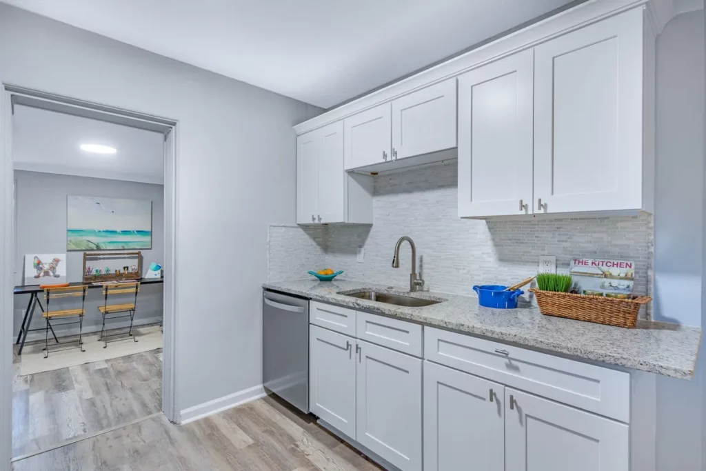 Jacksonville, FL kitchen with white shaker cabinets, granite countertops, stainless steel dishwasher, and tiled backsplash
