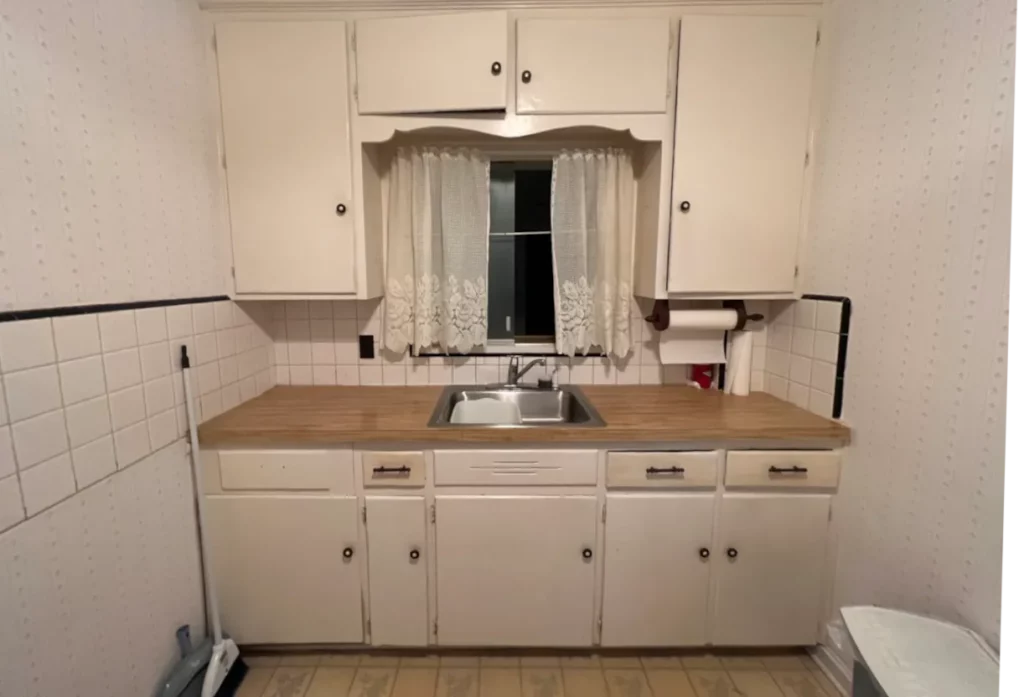 Kitchen with white cabinets, wood countertop, double-basin sink, tiled backsplash, and curtained window in Jacksonville, FL