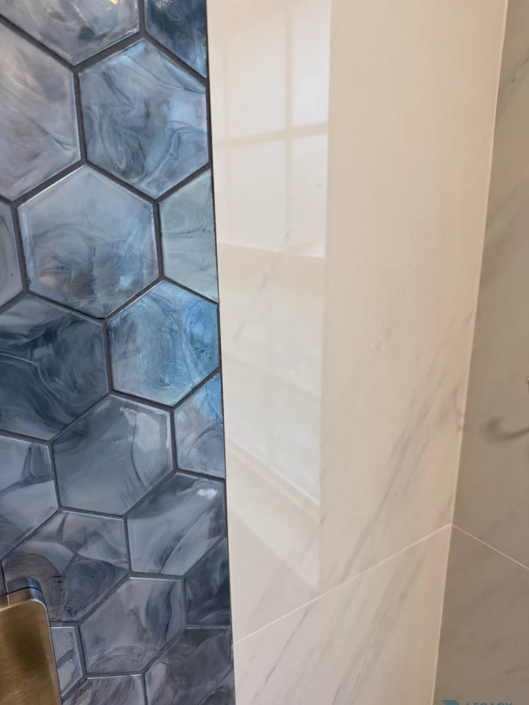 Close-up of blue marbled hexagon tiles beside large light-colored shower wall tiles in Jacksonville, FL