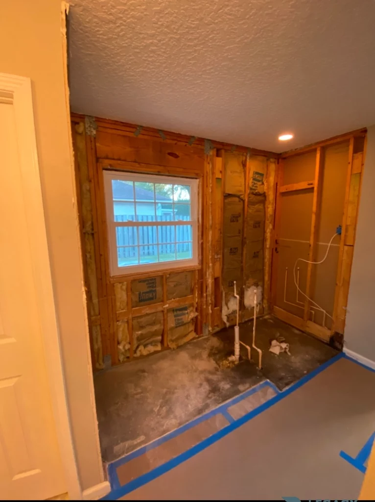 Bathroom with exposed wall framing, insulation, plumbing lines, and a window during a waterfall shower remodel in Jacksonville, FL