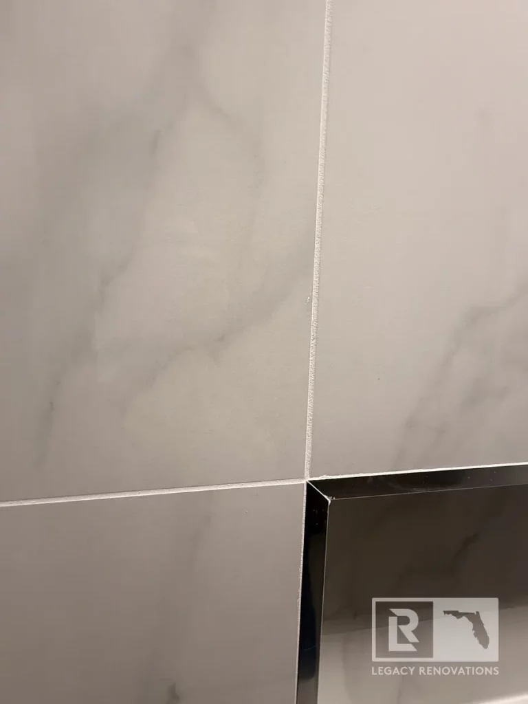 Close-up of marble-look shower wall tile with black-trimmed recessed niche in San Jose, Jacksonville, FL