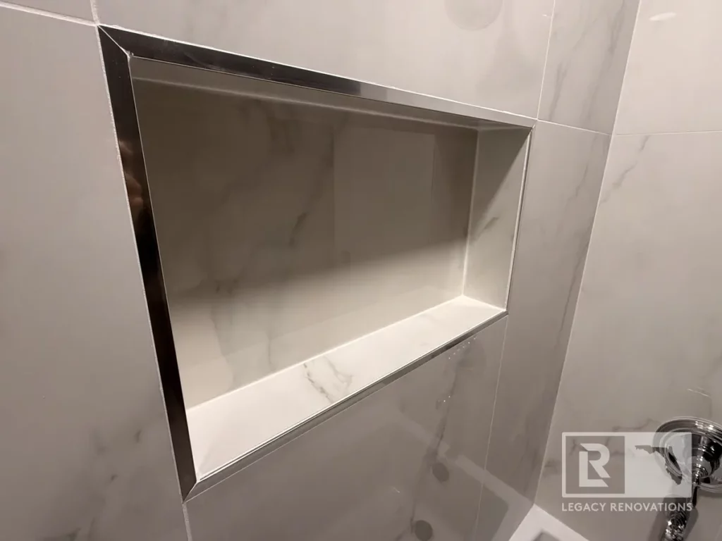 Recessed shower niche with dark trim surrounded by marble-look wall tile in San Jose, Jacksonville, FL