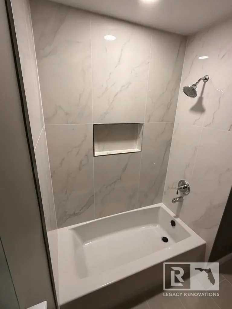 White bathtub with marble-look wall tile, recessed niche, chrome fixtures, and recessed lighting in San Jose, Jacksonville, FL