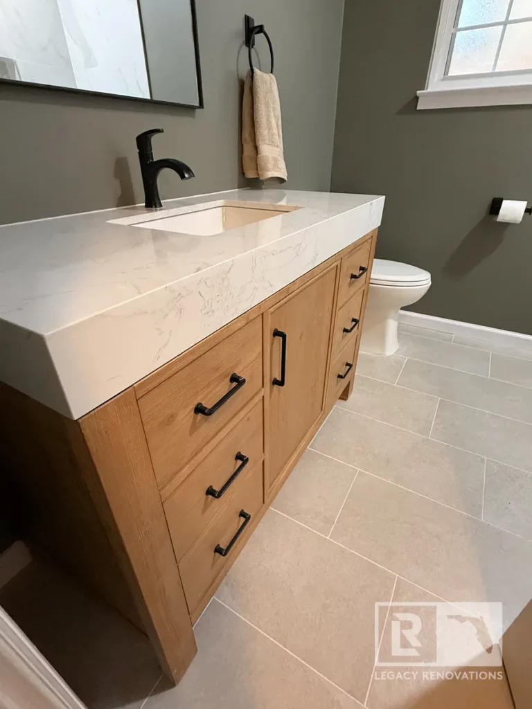 Natural wood bathroom vanity with white quartz countertop, black faucet, and tile floor in San Jose, Jacksonville, FL
