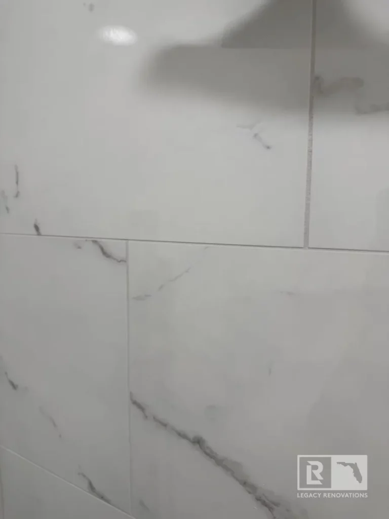 Close-up of large-format marble-style tiles with soft gray veining, smooth polished finish, and precise grout lines in Autumn Green, Jacksonville, FL.
