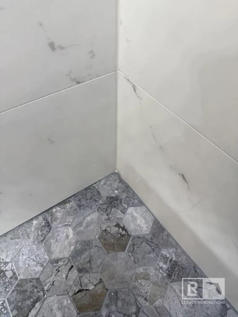 Shower with white marble-style tiles, gray veining, and a rainfall showerhead in Autumn Green, Jacksonville, FL.