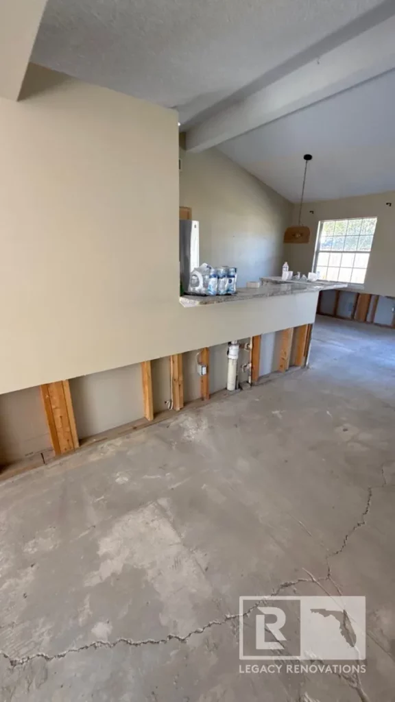 Interior home renovation featuring a raised bar counter, exposed lower wall studs, plumbing pipes, and concrete subfloor on Laura Rose Ct in Jacksonville, FL.