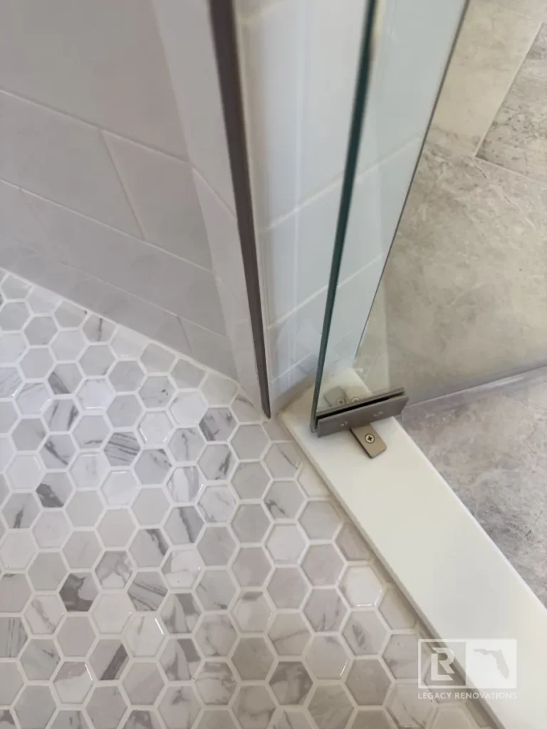 A luxurious shower renovation with custom tile work, high-end finishes, and glass doors, complementing the existing vanity and granite countertops.