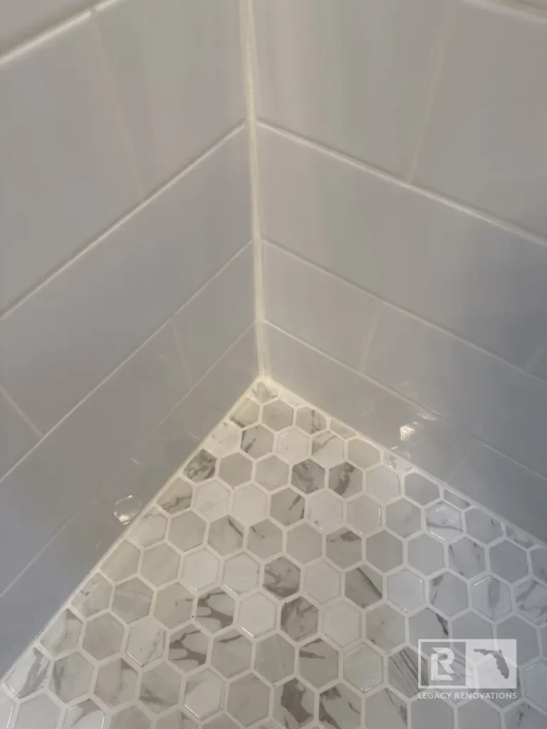 The shower walls feature classic white subway tiles, complemented by a built-in niche with textured hexagonal tiles for contrast.