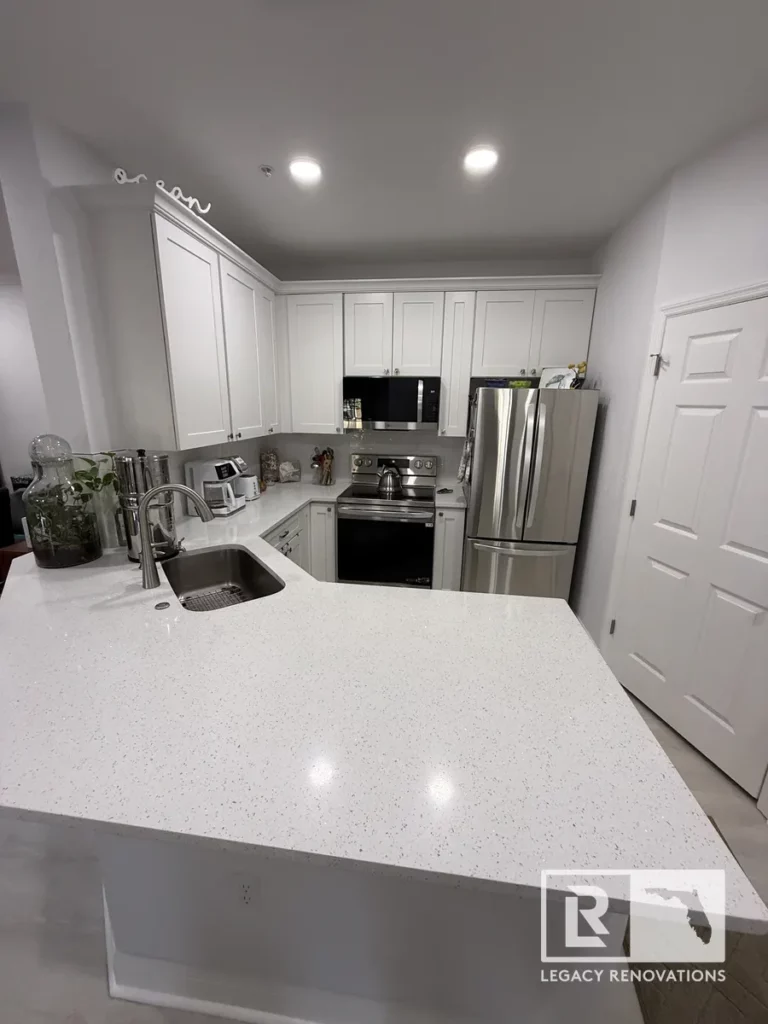 White kitchen cabinets, quartz island, stainless steel appliances, and undermount sink in St. John, Jacksonville, FL