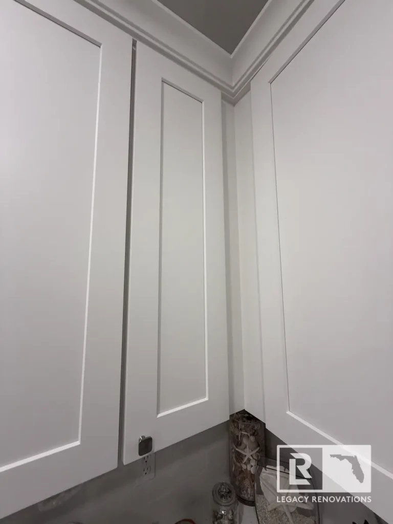 White raised-panel upper cabinets with crown molding in a St. John kitchen, Jacksonville, FL