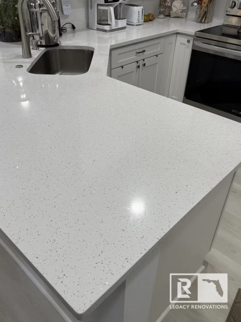 White quartz countertop with grey specks, featuring an undermount stainless steel sink and stainless steel gooseneck faucet in Jacksonville, FL.