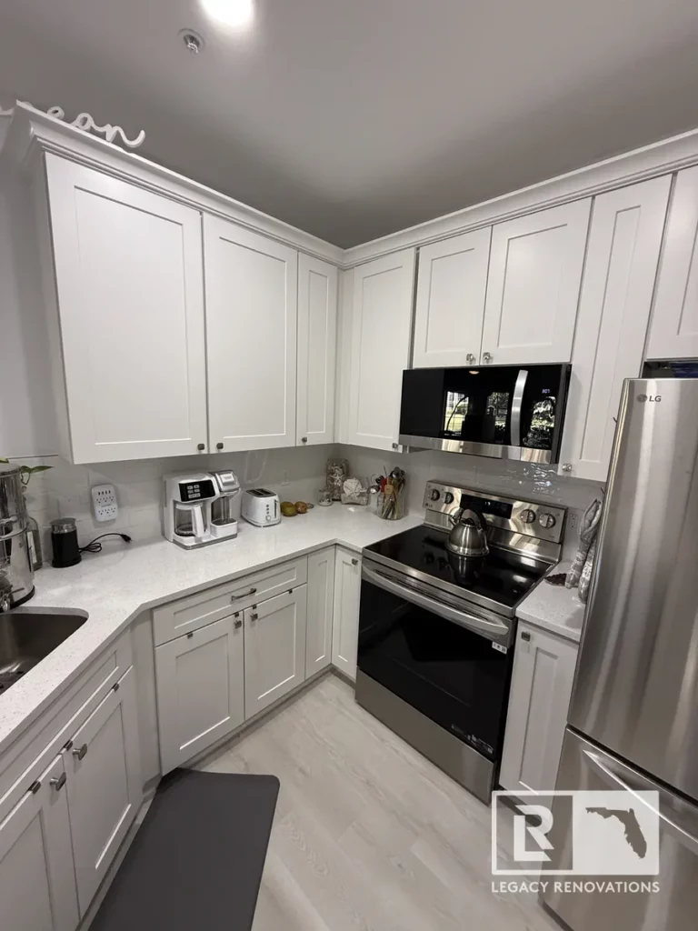 L-shaped kitchen with white shaker wall and base cabinets, crown molding, stainless steel range, built-in microwave, and stainless refrigerator in Jacksonville, FL.
