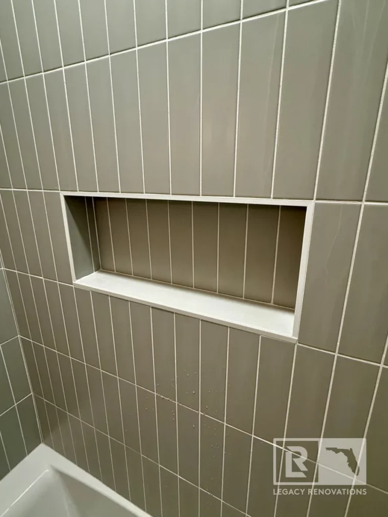 Recessed wall niche with gray vertical rectangular tile and white ledge above a bathtub in Jacksonville, FL