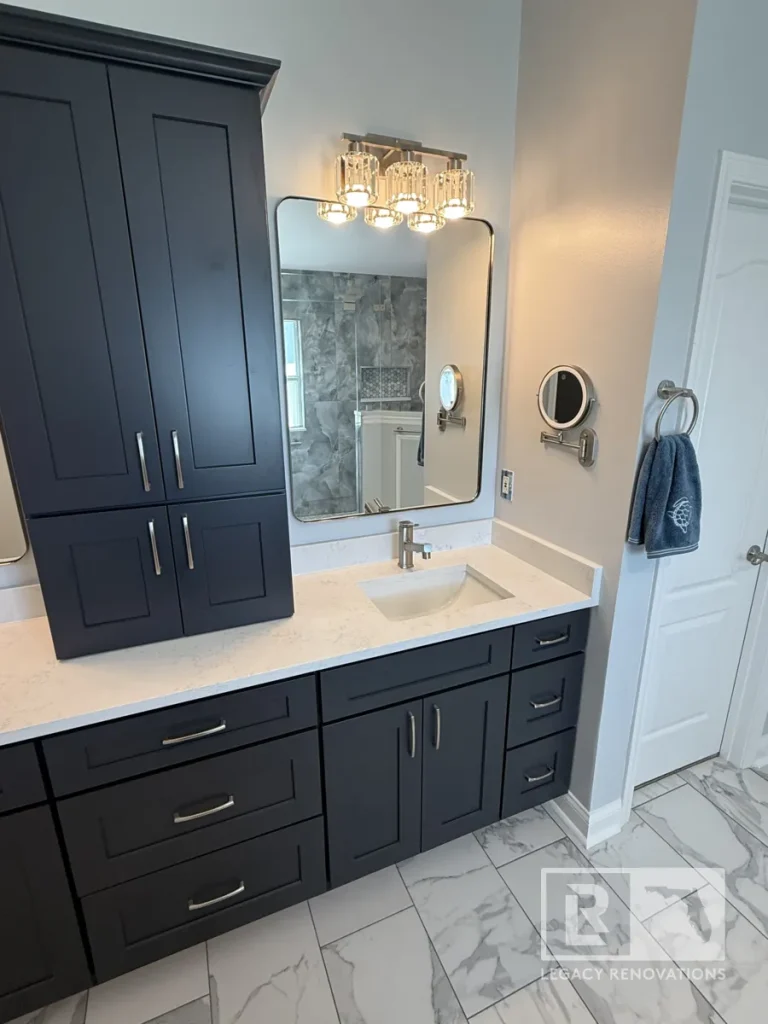 Dark blue vanity set with lower drawers, an integrated countertop linen cabinet, white quartz top, rectangular mirror, light fixture, and towel ring.