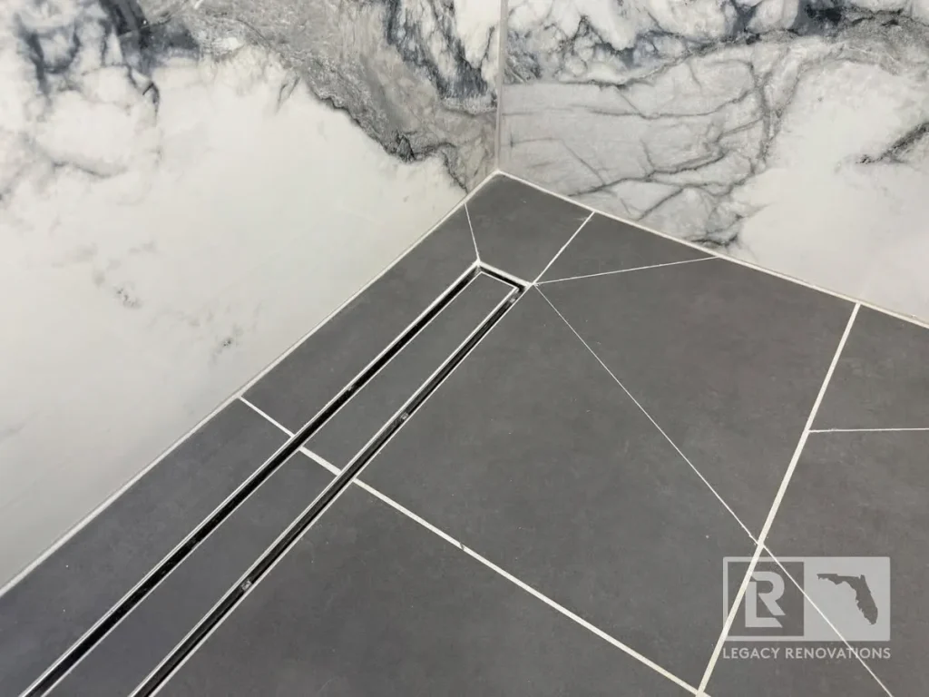 Gray tiled shower floor with linear drain and veined wall surround in Jacksonville, FL
