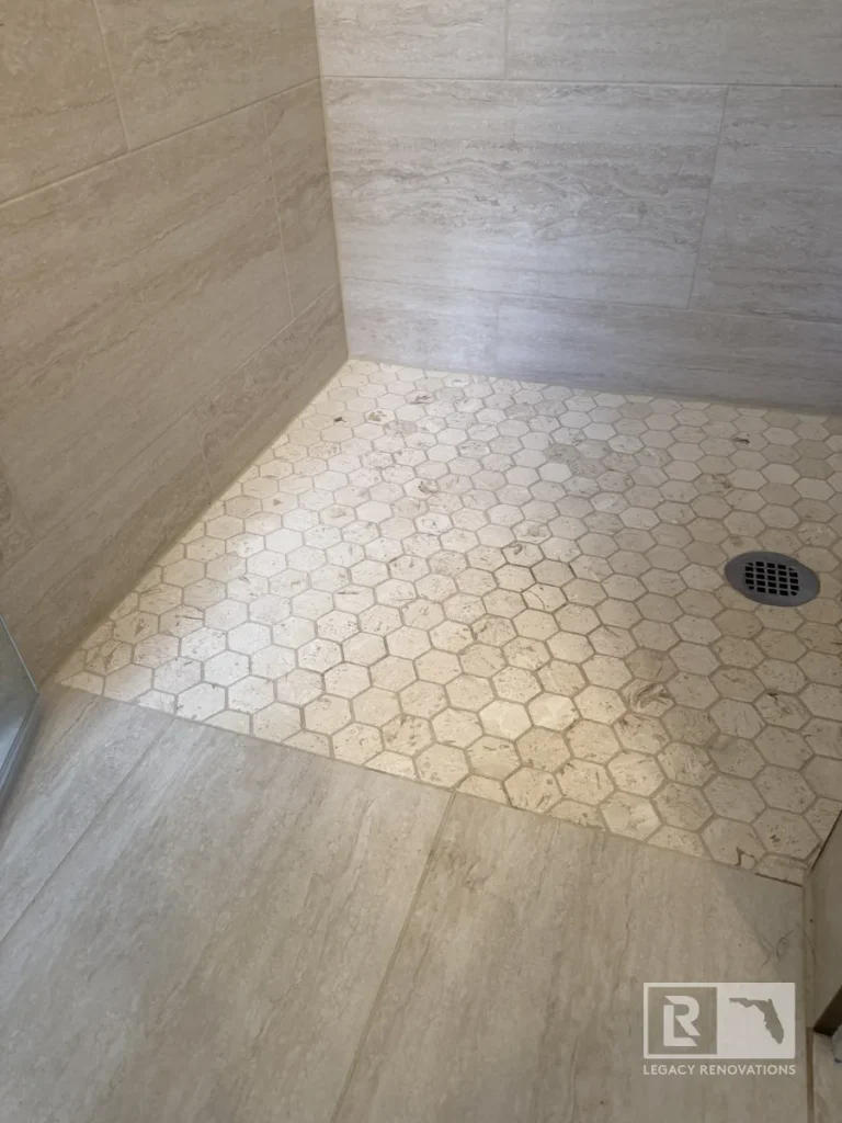 Cream hexagon tile shower floor with gray rectangular wall tiles and round drain in Jacksonville, FL