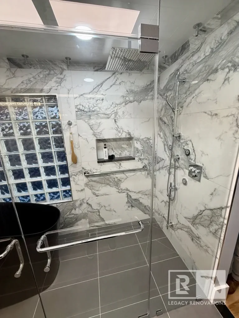Jacksonville, FL bathroom remodel with marble-look shower walls, glass enclosure, rainfall showerhead, and built-in niche