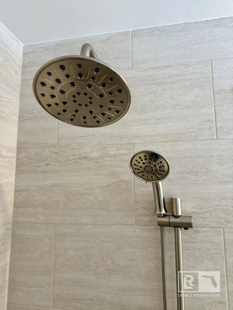 Large overhead showerhead and handheld showerhead mounted on light gray wall tile in Jacksonville, FL