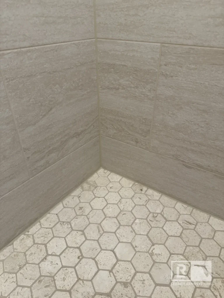 Cream hexagon shower floor tiles meeting gray rectangular wall tiles in Jacksonville, FL