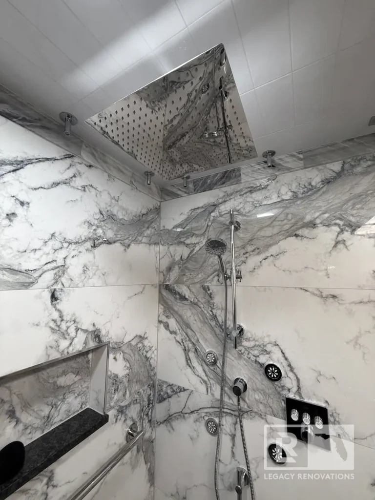 Large square ceiling showerhead with handheld fixture and veined wall panels in Jacksonville, FL