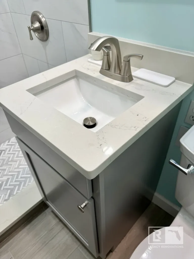 Compact bathroom vanity with a quartz countertop, undermount sink, brushed nickel faucet, and gray cabinetry in a Jacksonville, FL bathroom remodel.