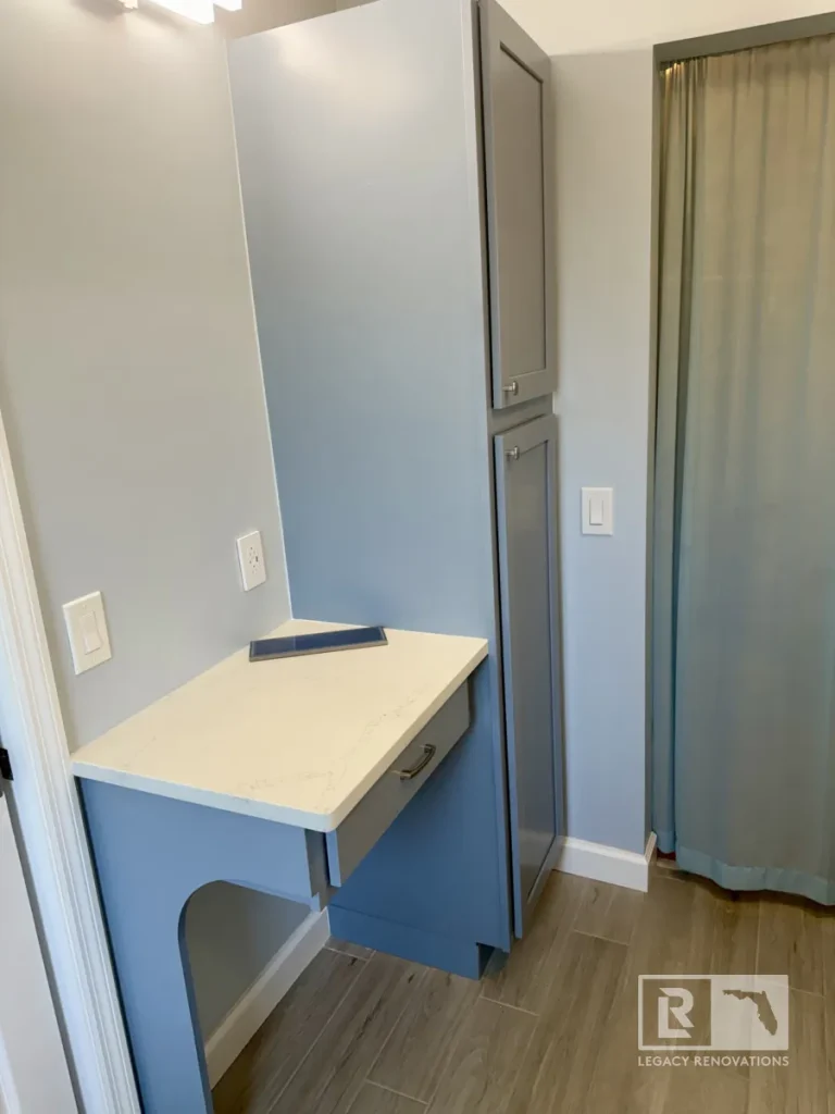 Custom gray bathroom storage cabinet with a quartz countertop, pull-out drawer, and tall linen cabinet in a Jacksonville, FL bathroom remodel.