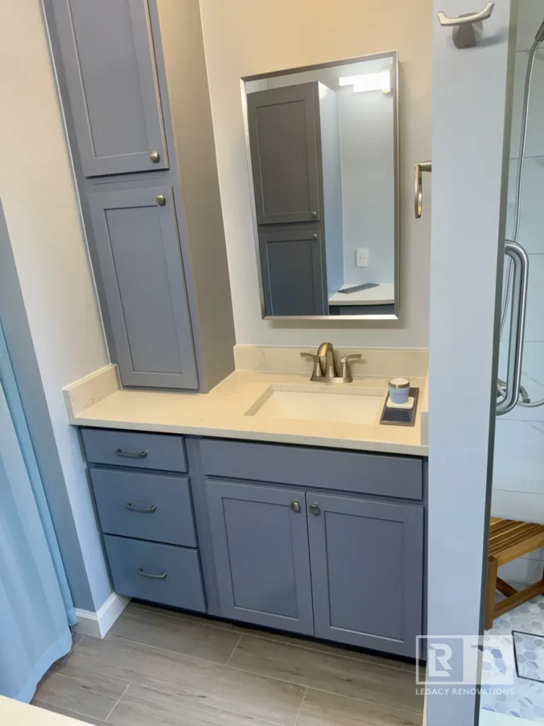 Modern gray bathroom vanity with a quartz countertop, integrated sink, brushed nickel faucet, tall storage cabinet, and custom cabinetry in a Jacksonville, FL bathroom remodel.