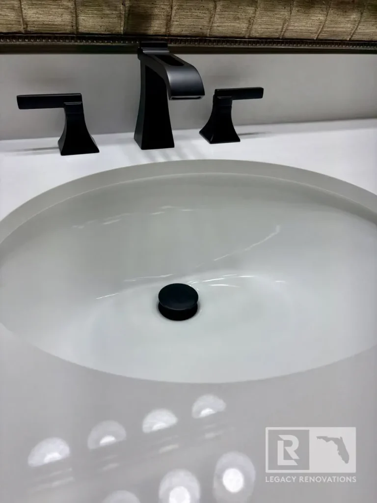 Modern bathroom vanity with a matte black widespread faucet, white undermount sink, quartz countertop, and matching black drain cover in Jacksonville, FL.