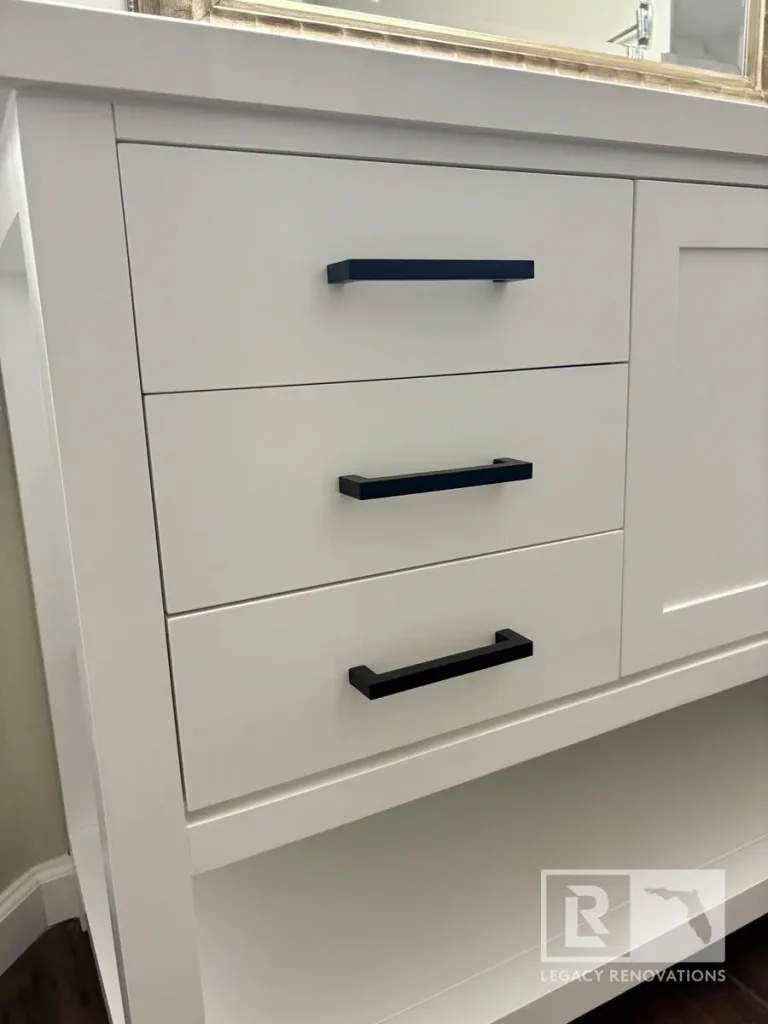 White shaker bathroom vanity featuring matte black drawer pulls and a quartz countertop in a modern bathroom remodel in Jacksonville, FL.