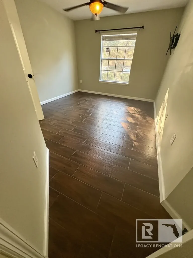 Empty room in San Pareil featuring newly installed wood-look porcelain tile flooring with neutral walls, white trim, and a ceiling fan.