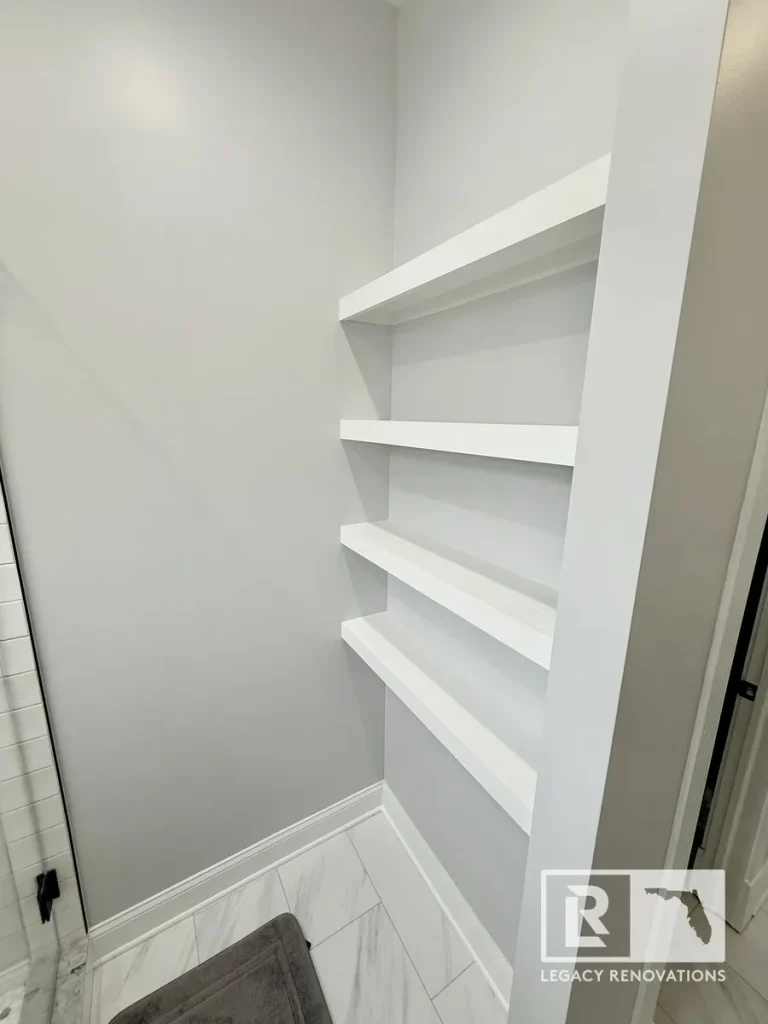 Built-in custom white floating shelves in a renovated bathroom alcove by a Jacksonville, FL contractor.