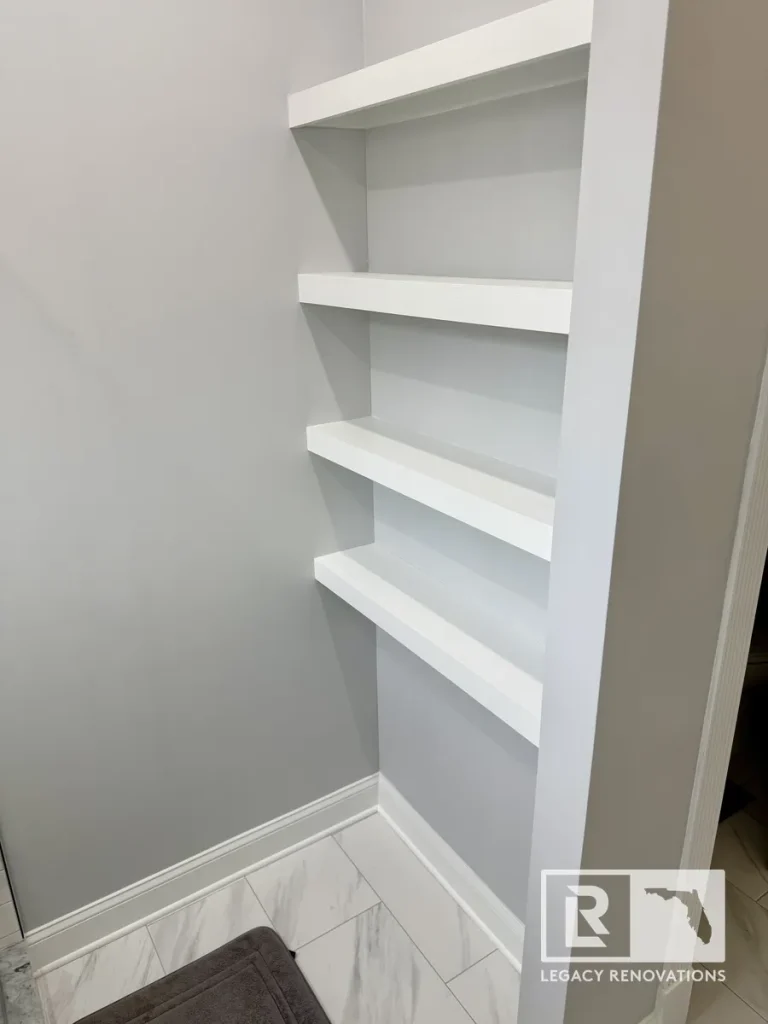 Custom built-in white bathroom shelves with a clean, recessed design, providing organized storage in a modern bathroom remodel.