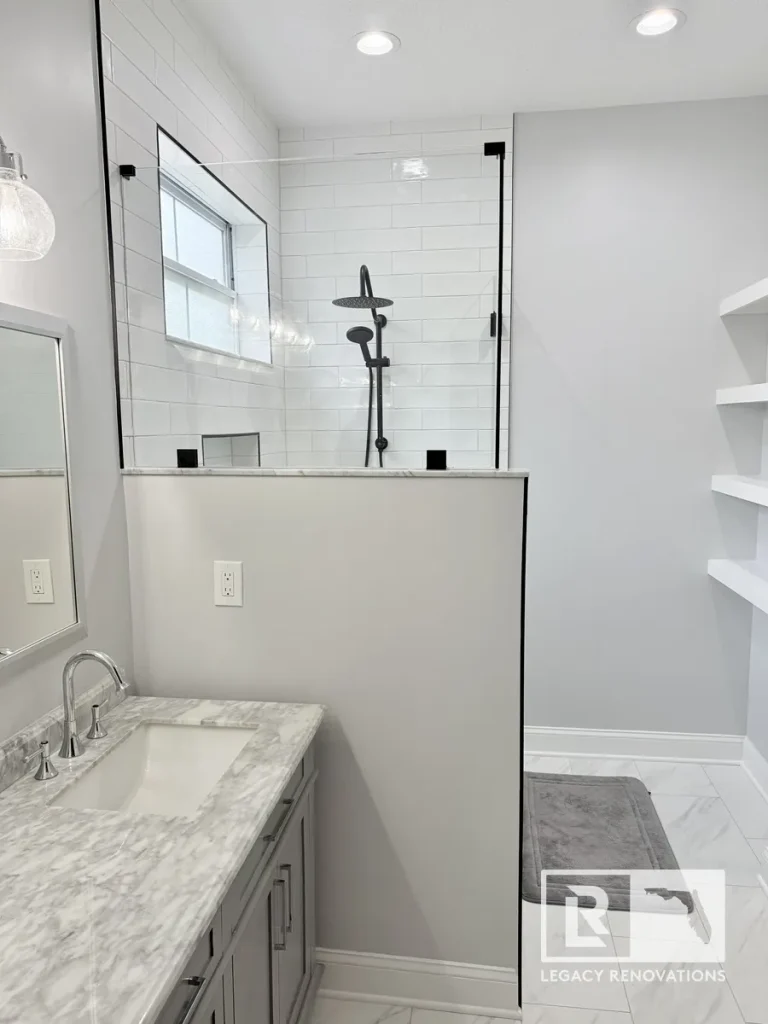 Modern bathroom featuring a frameless glass shower, white subway tile, gray vanity with marble countertop, built-in shelving, and matte black shower fixtures.