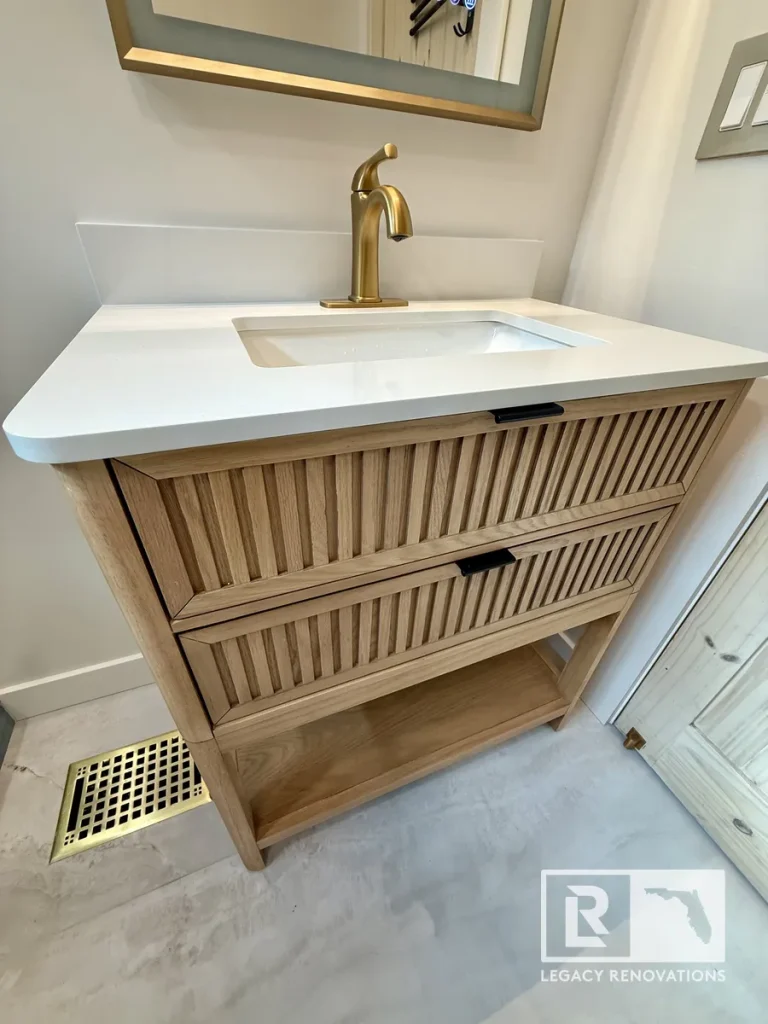 Oak bathroom vanity with white quartz countertop and brushed gold faucet in Jacksonville, FL.