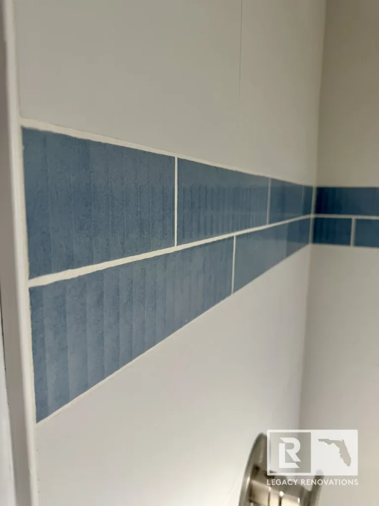 Close-up of blue accent wall tile with large-format white shower tile in a bathroom remodel in Jacksonville, FL.