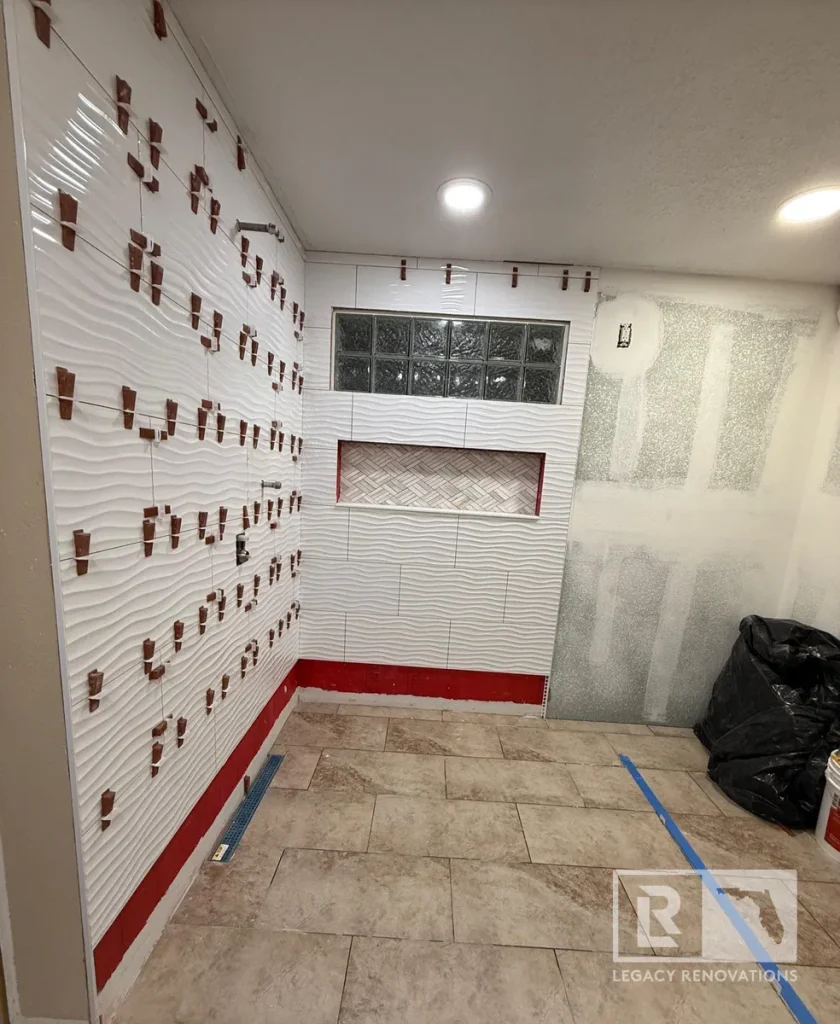 Walk-in shower tile installation with textured wall tile, niche, and porcelain floor in Jacksonville, FL.