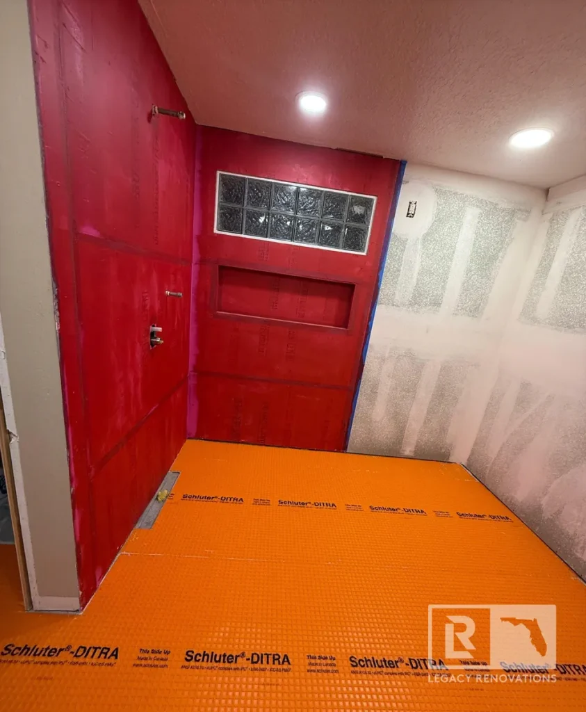 Walk-in shower waterproofing with RedGard walls, Schluter-DITRA floor membrane, recessed niche, and glass block window during a bathroom remodel in Jacksonville, FL.