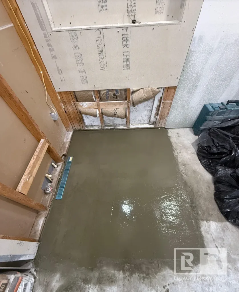 Freshly poured shower pan with linear drain during a walk-in shower remodel in Jacksonville, FL, showing the bathroom in the construction phase.