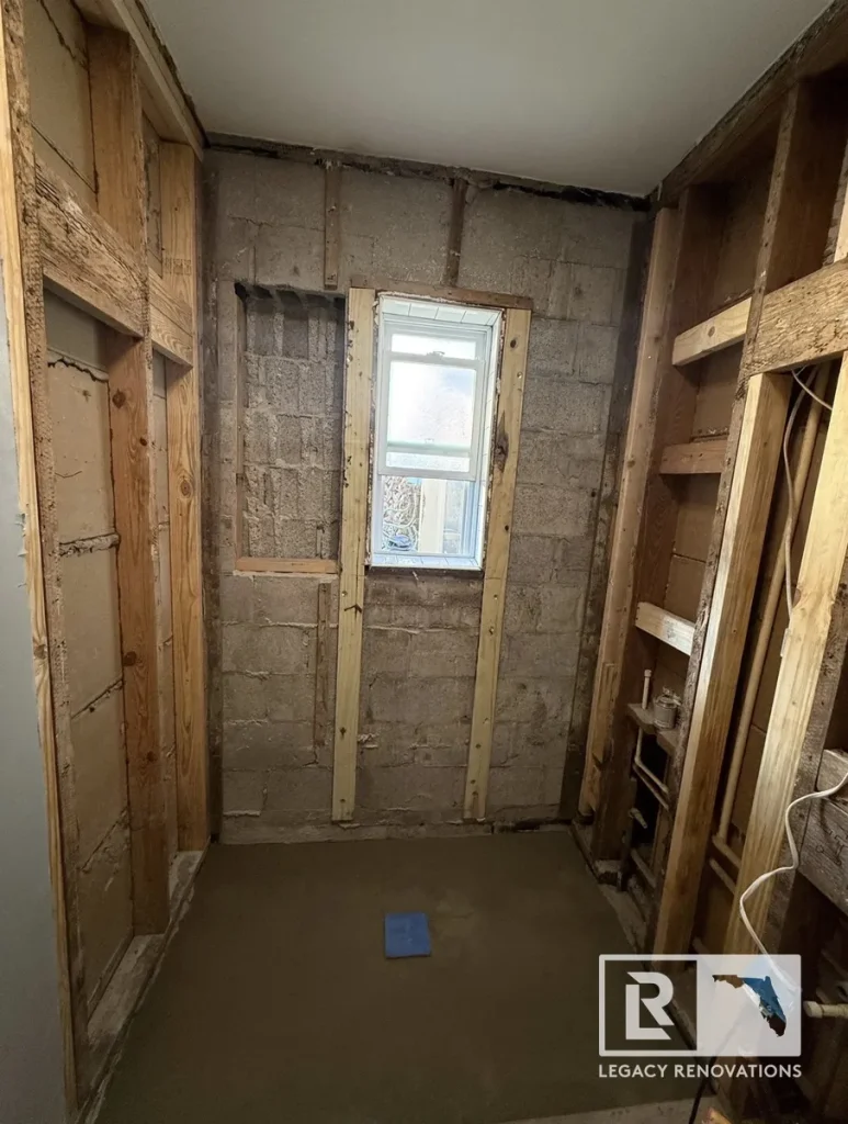 Bathroom shower framing with installed shower pan, recessed niche, and window during a bathroom remodel in Jacksonville, FL before waterproofing and tile installation.
