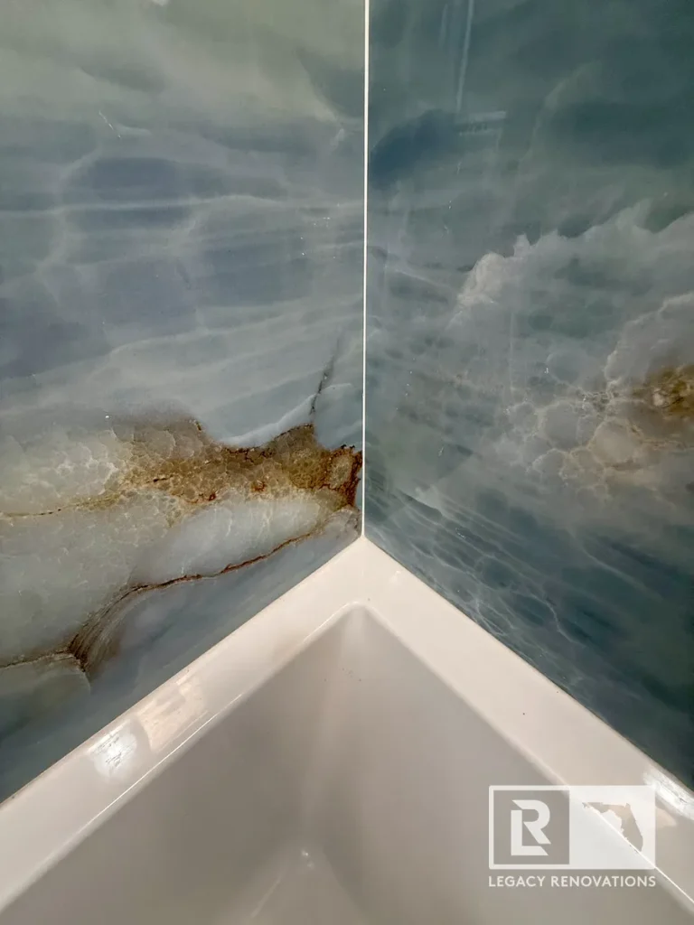 Close-up of blue porcelain shower wall tile meeting a white bathtub with seamless corner installation during a custom bathroom remodel in Jacksonville, FL.