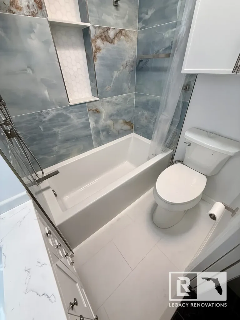Modern bathroom remodel with bathtub, frameless glass shower, dual recessed shower niches, blue porcelain wall tile, custom storage cabinet, and white vanity in Jacksonville, FL.