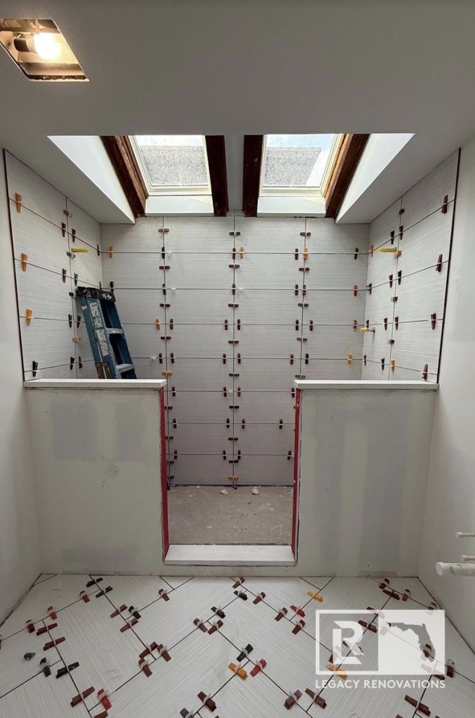 Bathroom remodel under construction featuring a walk-in shower with fresh wall and floor tile, levelers, and dual skylights by Legacy Renovations in Jacksonville, FL.