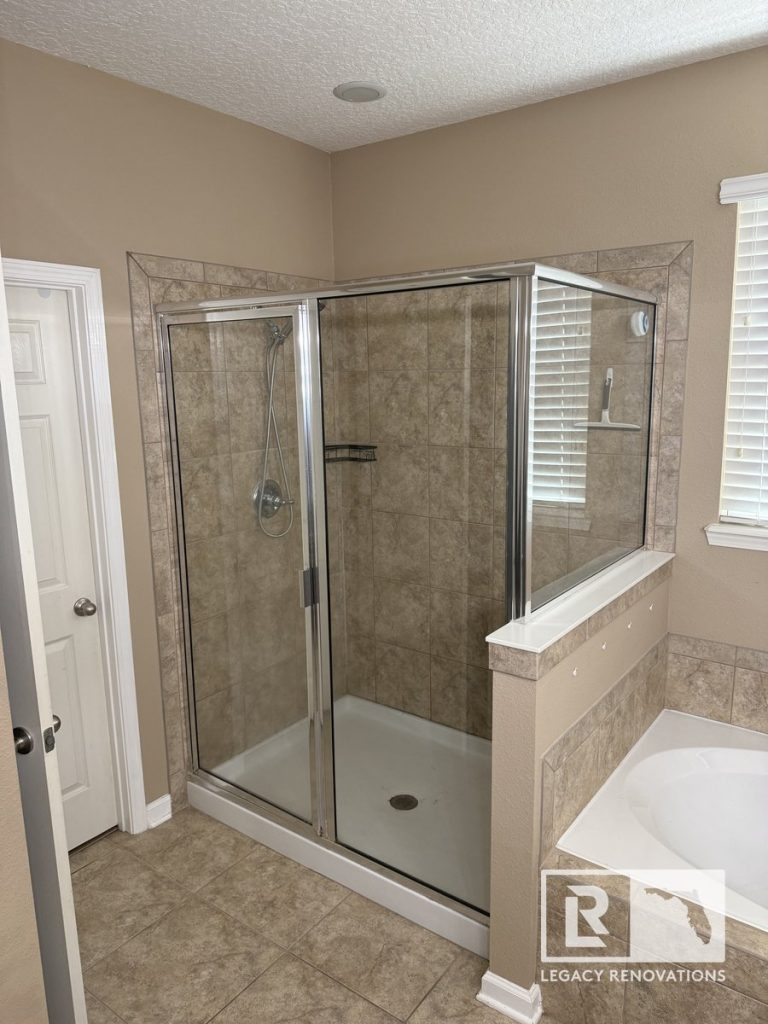 Before bathroom remodel in Jacksonville, Florida showing the original tiled walk-in shower with framed glass enclosure, built-in soaking tub, ceramic tile surround, and pre-remodel bathroom layout.