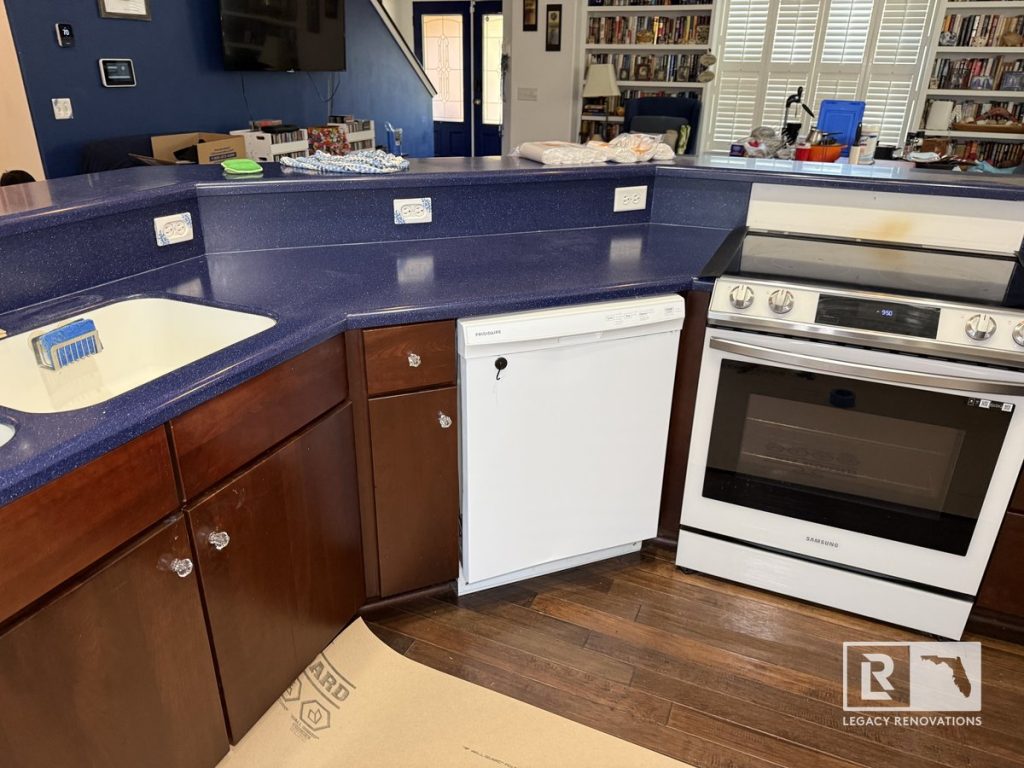 Before kitchen renovation with wraparound breakfast bar, dark wood cabinets, blue countertops, white dishwasher, freestanding range, and open-concept layout in a Jacksonville, Florida home.