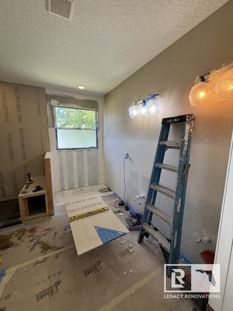 Bathroom remodel in progress in Jacksonville, Florida showing shower construction, new drywall, recessed lighting, vanity installation area, and preparation for tile and plumbing fixtures.