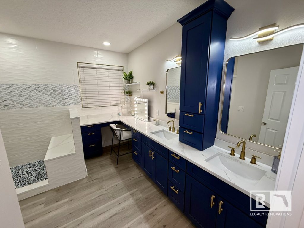 Luxury bathroom remodel in Jacksonville FL featuring a navy-blue double vanity, quartz countertops, gold fixtures, designer mirrors, and a custom walk-in shower.