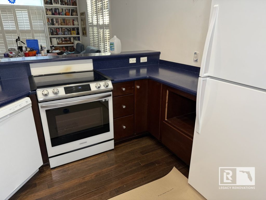 Before kitchen remodel featuring an L-shaped layout with dark wood cabinets, blue countertops, white refrigerator, electric range, and dishwasher in a Jacksonville, Florida home.