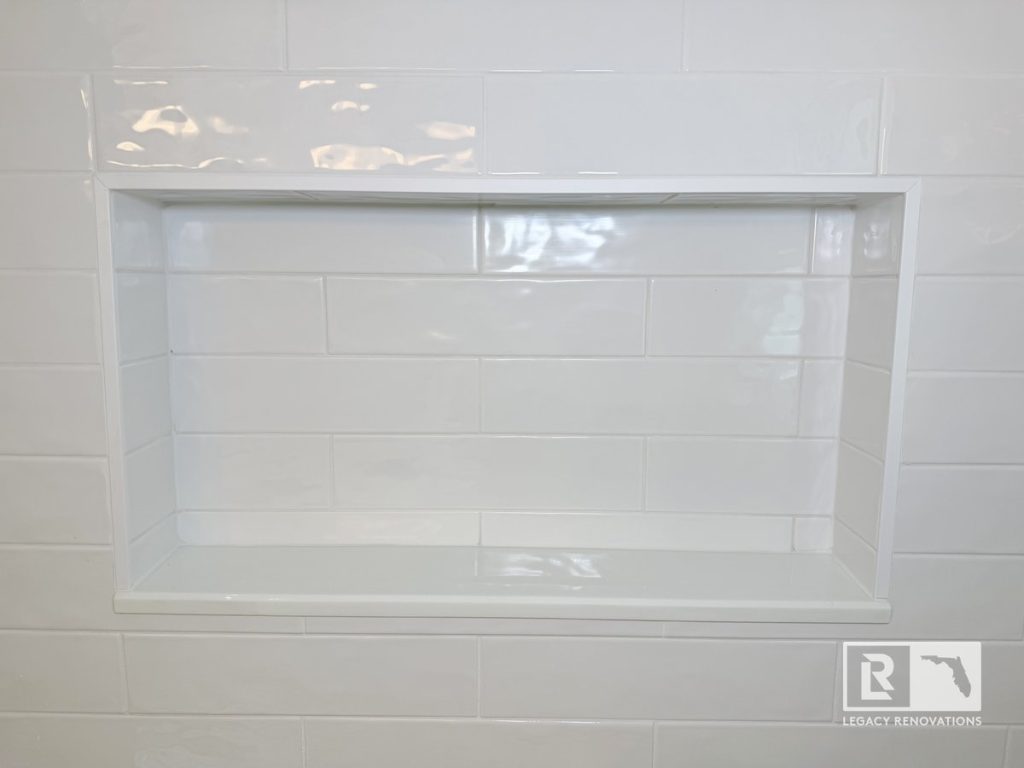 Custom recessed shower niche with glossy white subway tile in a modern bathroom remodel completed in Jacksonville, Florida.