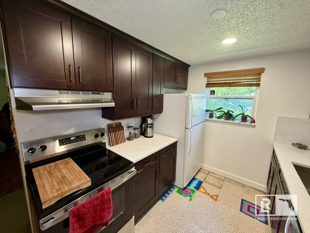 Wide view of a remodeled galley kitchen with espresso shaker cabinets, quartz countertops, stainless steel appliances, and recessed lighting.